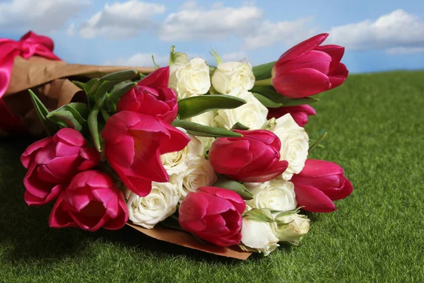 Buquê de tulipas rosa e rosas brancas na grama verde — Fotografia de Stock