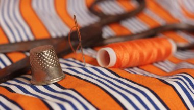 Turuncu ve beyaz çizgili kumaş üzerinde turuncu iplik ve yüksük makarası