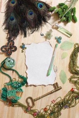 Yeşil Mücevherler ve Tavuskuşu tüyleriyle çevrili Eski Yanmış Kağıt ve Antika Anahtar Ahşap Arkaplanda