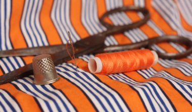 Turuncu ve beyaz çizgili kumaş üzerinde turuncu iplik ve yüksük makarası