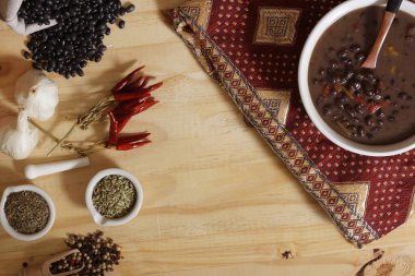 Baharatlı ve kuru fasulyeli, ahşap masadaki siyah fasulye. Kasenin altında eski kumaş