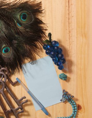 Tahta Masa Üzerinde Not ve Kalem Etrafı Tavuskuşu tüyleri ve Mücevherleriyle çevrili