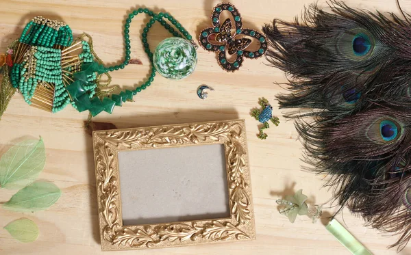 Green Jewelry and Peacock Feathers With Gold Picture Frame on Wood Back