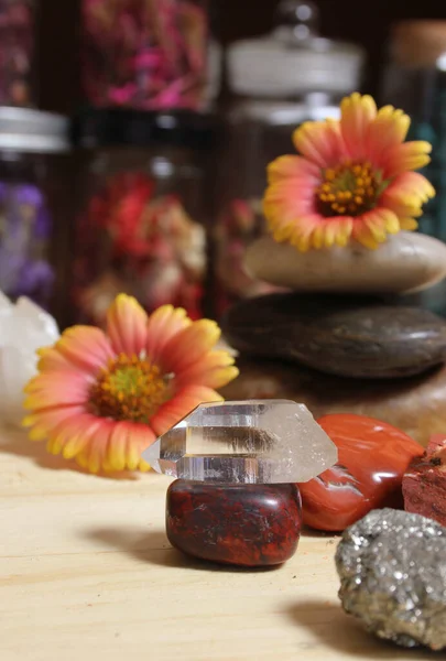 Quartz Crystal Balanced on Bloodstone With Flowers in Background