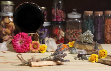 Meditation Altar With Rock Crystals and Flowers. Large Obsidian Crystal Ball in Center Jars of Herbs in Background