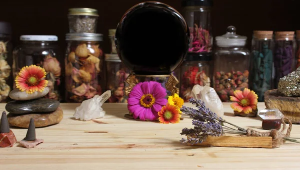 Meditation Altar With Rock Crystals and Flowers. Large Obsidian Crystal Ball in Center Jars of Herbs in Background