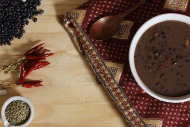 Baharatlı ve kuru fasulyeli, ahşap masadaki siyah fasulye. Kasenin altında eski kumaş
