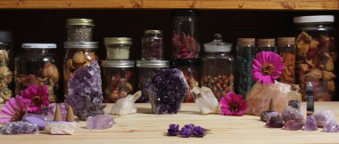 Amethyst Crystals and Flowers On Meditation Table With Jars of Dried Herbs in Background