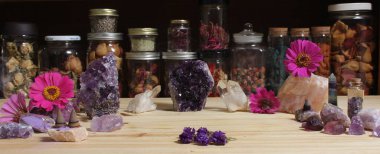 Amethyst Crystals and Flowers On Meditation Table With Jars of Dried Herbs in Background