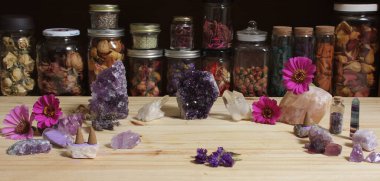 Amethyst Crystals and Flowers On Meditation Table With Jars of Dried Herbs in Background
