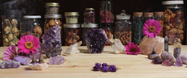 Amethyst Crystals and Flowers On Meditation Table With Jars of Dried Herbs in Background