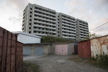 VLADIVOSTOK, RUSSIA - 03 / 09 / 2021 Bir Sovyet terk edilmemiş, balkonlu beton ev binası ve önünde Rusça ve eski kırmızı garajlarda seni seviyoruz yazan bir yazı.