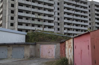 VLADIVOSTOK, RUSSIA - 03 / 09 / 2021 Bir Sovyet terk edilmemiş, balkonlu beton ev binası ve önünde Rusça ve eski kırmızı garajlarda seni seviyoruz yazan bir yazı.