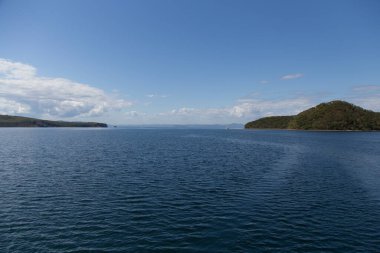 Rusya 'nın Vladivostok adasındaki Russky adasındaki Novik limanında deniz manzarası, adalar, pelerinler, beyaz bulutlar ve mavi gökyüzü