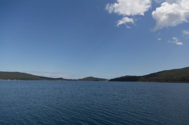 Rusya 'nın Vladivostok adasındaki Russky adasındaki Novik limanında deniz manzarası, adalar, pelerinler, beyaz bulutlar ve mavi gökyüzü