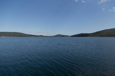 Rusya 'nın Vladivostok adasındaki Russky adasındaki Novik limanında deniz manzarası, adalar, pelerinler, beyaz bulutlar ve mavi gökyüzü