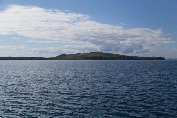Rusya 'nın Vladivostok adasındaki Russky adasındaki Novik limanında deniz manzarası, adalar, pelerinler, beyaz bulutlar ve mavi gökyüzü