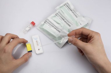 Sağ elinde kan koleksiyoncusu pasteti, sol elinde neşter, negatif sonuç antijen koronavirüs covid-19 pandemik test örneği, solüsyon, beyaz arka planda paketler.