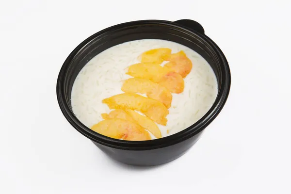 在白色背景的黑色塑料碗中 有桃子果片的美味白米粥被隔离在角落拍摄的照片 — 图库照片