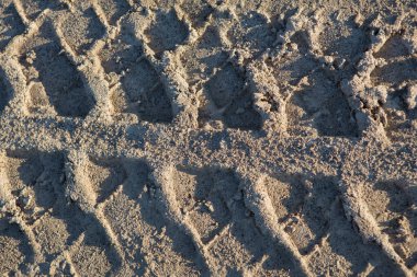 Detaylı doldurulmuş çerçeve. Araba lastiği izleri, çamurlu kum yolu yüzeyindeki izler yakın çekim.