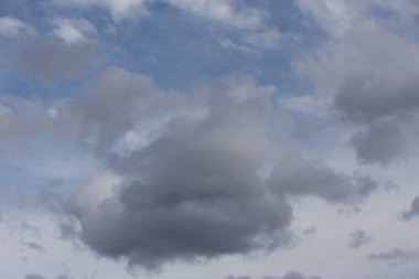 Pofuduk, dramatik, beyaz ve gri bulutların altında derin mavi bir arka planda güzel bir gün bulutlu manzarası.