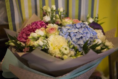 Pembe ve mavi Hydrangea Hortensia çiçekleriyle güzel bir buket, beyaz ve sarı güller, kağıda sarılı yan manzara