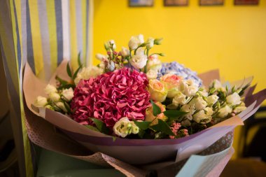 Pembe ve mavi Hydrangea Hortensia çiçekleriyle güzel bir buket, beyaz ve sarı güller, kağıda sarılı yan manzara