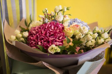 Pembe ve mavi Hydrangea Hortensia çiçekleriyle güzel bir buket, beyaz ve sarı güller, kağıda sarılı yan manzara