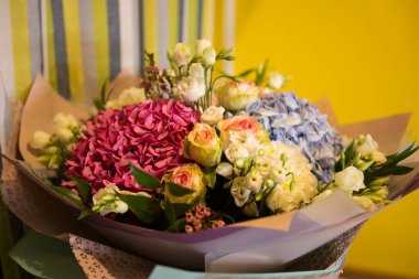 Pembe ve mavi Hydrangea Hortensia çiçekleriyle güzel bir buket, beyaz ve sarı güller, kağıda sarılı yan manzara