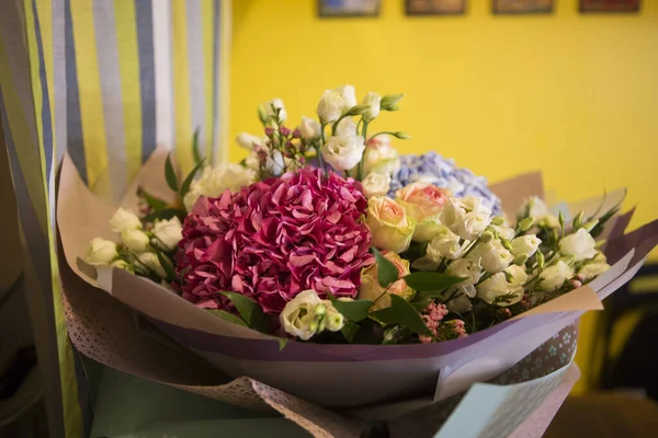 Pembe ve mavi Hydrangea Hortensia çiçekleriyle güzel bir buket, beyaz ve sarı güller, kağıda sarılı yan manzara