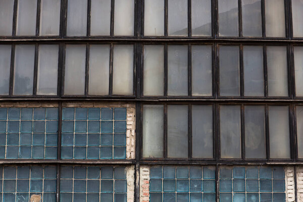 Old soviet constructivist industrial building exterior facade with large windows, blue glass bricks.