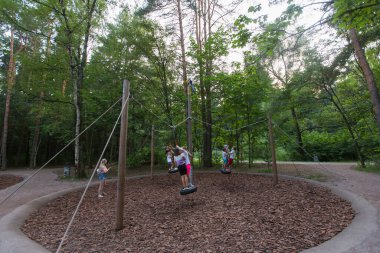 MOSCOW, RUSSIA - 09/08/2021  standing platform swings on children's playground made of environment and eco-friendly wooden materials. Gorod Ptits (Birds City), Meshersky park in a pine forest. 