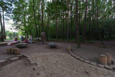 MOSCOW, RUSSIA - 09.08.2021  spinning rocks and stones and tree log stump benches at children's playground. Gorod Ptits (Birds City), Meshersky park in a pine forest. 