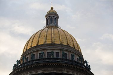 SAINT PETERSBURG, RUSSIA 15.08.2021 Saint Isaac's Cathedral golden cupola dome and statues close up on grey sky background