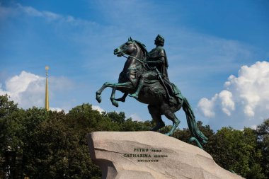 SAINT PETERSBURG, RUSSIA - 08.2021 Bronze Horseman equestrian sculpture of Peter the Great side view, with the Admiralty spire, blue sky and white clouds background