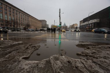 MOSCOW, RUSSIA 23.01.2021 kirli, siyah, ıslak, ıslak, ıslak, ıslak kar, asfalt yoldaki büyük su birikintisi ve yaya geçidindeki insanlar. İç karartıcı kış buzları. Maykovskaya Meydanı