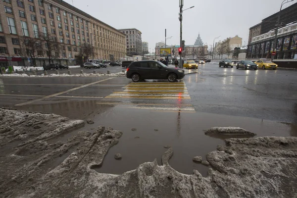 MOSCOW, RUSSIA 23.01.2021 kirli, siyah, ıslak, ıslak, ıslak, ıslak kar, asfalt yoldaki büyük su birikintisi, arabalar ve yaya geçidindeki insanlar. İç karartıcı kış buzları. Maykovskaya Meydanı