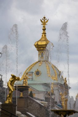 PETERHOF, SAINT PETERSBURG, RUSSIA - 15.08.2021 Altın kubbe Sarayda iki başlı kartal ve Büyük Şelale ve Samson Çeşmesi 'nin su dereleri. Dikey gri gökyüzü dikey çekim