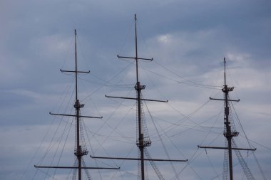 Gri gökyüzünde ve bulutların ardında 13 yüzyılın yelkenli gemisi Hollanda Fluyt ticaret gemisinin üç tahta direği.