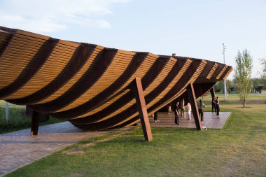 Moskova, Rusya 08.08.2021 modern kahverengi ahşap pergola ve çatıda dans eden insanlar. Çimenler, kaldırım taşları. Tyufeleva Roshcha Parkı, Zilart. ! melk peyzaj mimarisi şehir tasarımı