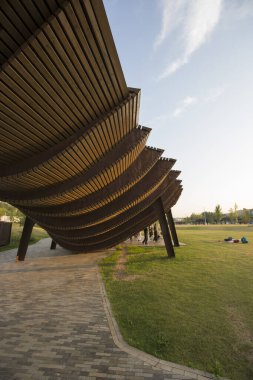 Moskova, Rusya 08.08.2021 modern kahverengi ahşap pergola ve çatıda dans eden insanlar. Çimenler, kaldırım taşları. Tyufeleva Roshcha Parkı, Zilart. ! melk peyzaj mimarisi şehir tasarımı