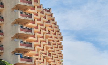 Merdivenler, balkonlu ve mavi gökyüzü ve bulutlu pencereli bir tatil binası.