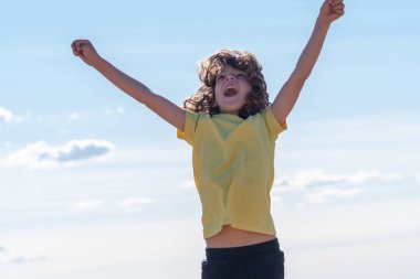 Uzun saçlı, gülümseyen şirin çocuk zıplayarak ve oynayarak eğleniyor. eğlence, eğlence ve boş zaman konsepti