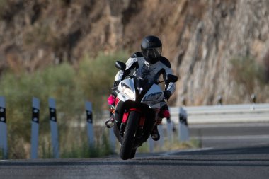 biker person with safety helmet and protective suit driving on the asphalt road