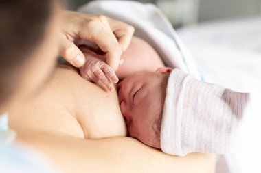 Anne yeni doğmuş bebeğini hastanede emzirirken küçük elinin parmaklarını tutuyor.