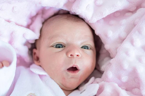 一个新生女婴张开嘴躺在床上铺在柔软的粉红色毯子上的画像 — 图库照片