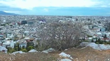 Kamera ön planı izliyor ve bulutlu bir günde Atina kentinin yüksek açılı manzarasını izliyor.