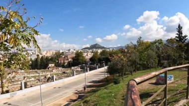 Yüksek açıdan 4k 'lik hızlandırılmış video, güneşli bir günde Atina' nın Ermou Caddesi 'nde yürüyen insanları gösteriyor. Lycabettus tepesi arka planda bulutlar geçerken.