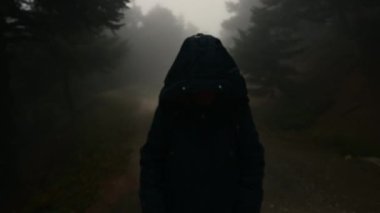 Kamera görüntülerine göre uzun ceketli ve kapüşonlu bir kadın toprak bir yolda duruyor. Şiddetli sisli bir ormanda çekilen görüntüler tüyler ürpertici bir his yaratıyor..