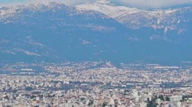 Atina 'nın kalabalık bölgelerine ve Atina-Yunanistan' daki Parnitha dağının karlı zirvesine bakan kameraya odaklan.